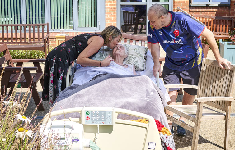 Image: St Helena Hospice patient with daughter and son in a hospital bed in the hospice garden