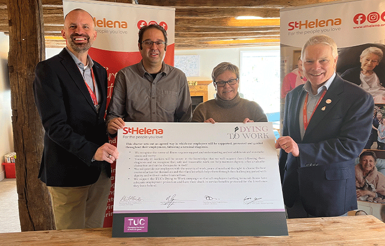 Four smiling people holding a large signed Dying to Work charter