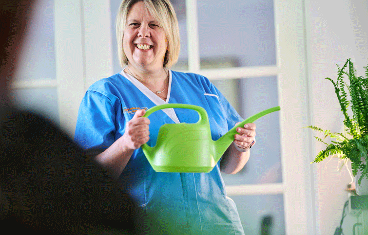 Carer from St Helena care and support holding watering can in  client home