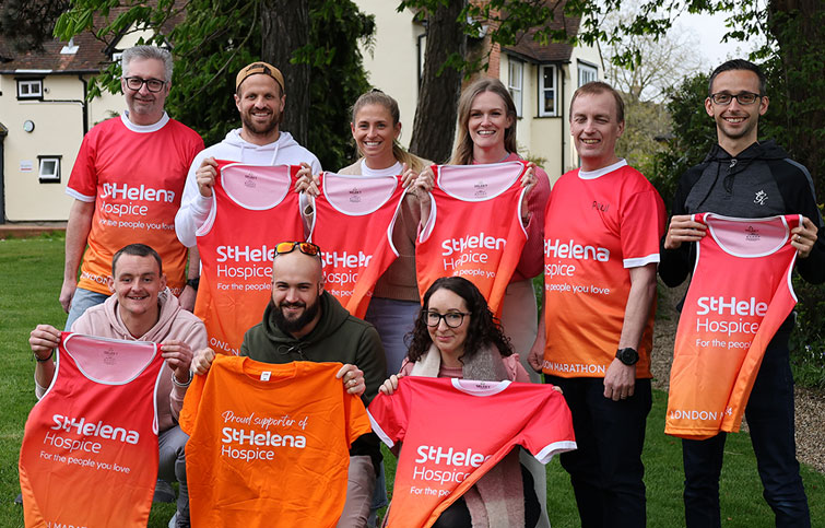 Image: London Marathon runners holding orange running tops with St Helena logo