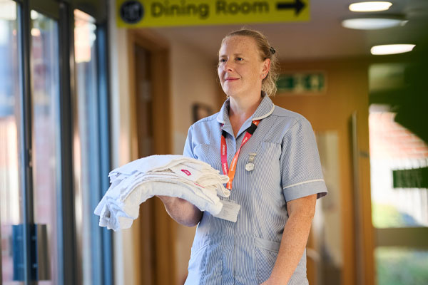 Clinical support worker holding towels on the in-patient unit