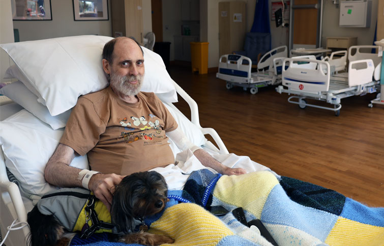 Image: Bradley with his dog in a bed at St Helena Hospice