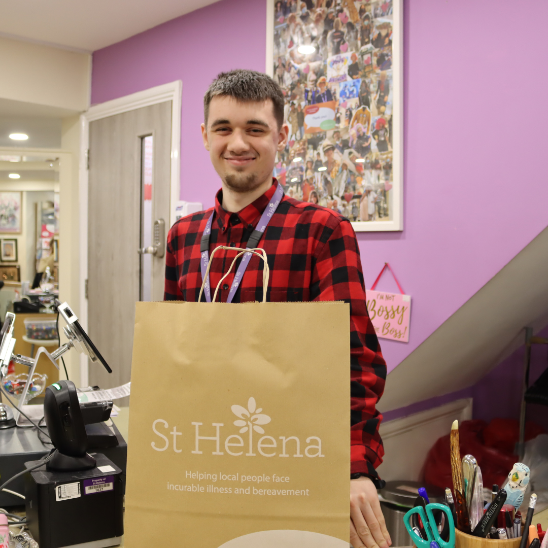 A retail volunteer smiling behind the till