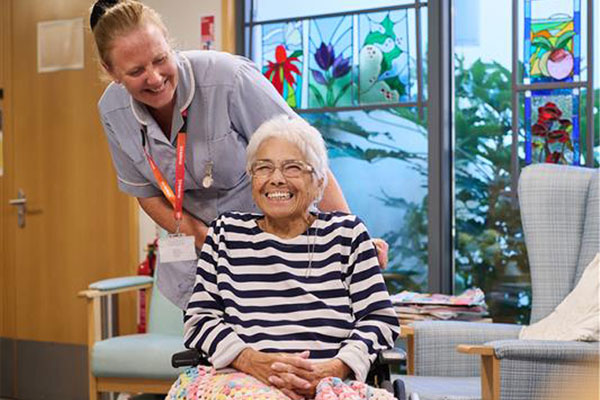 Clinical Support Working smiling with a patient in a wheel care with text that reads play care win
