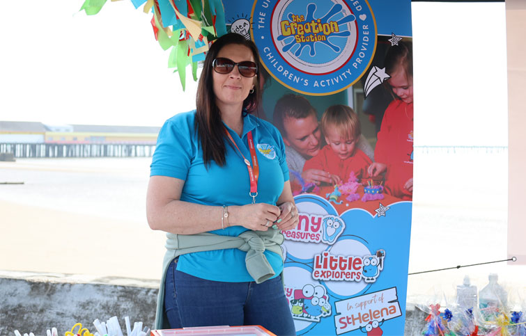 Creation Station staff standing proudly with banner in background by the sea in north Essex area