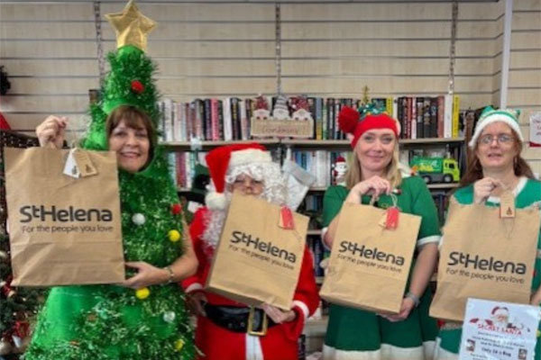 St Helena retail team dresses in Christmas outfits holding Mystery Secret Santa Bags