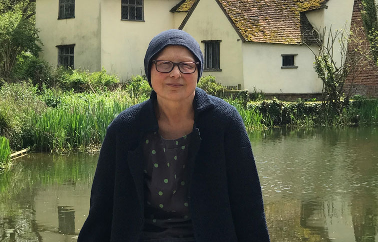 Viv looking at the camera with pond and old historic building behind her