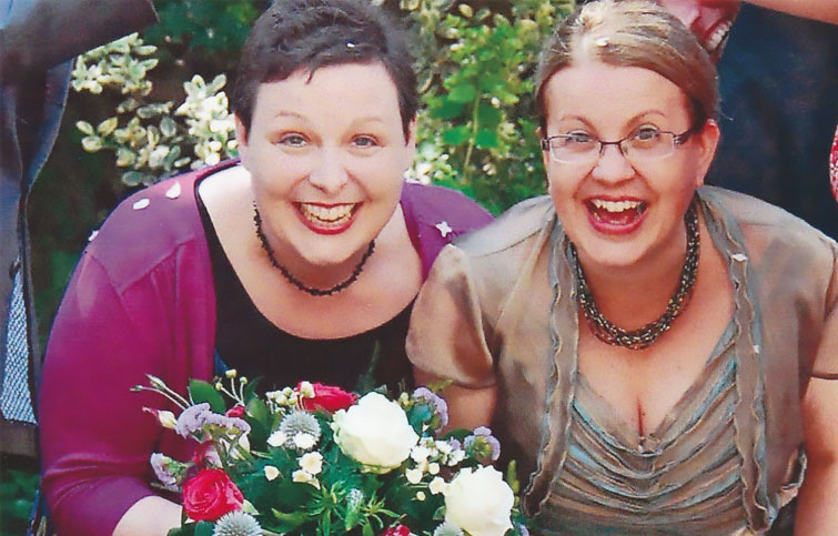 Viv and Rachel smiling at the camera, Viv is holding a bouquet of flowers